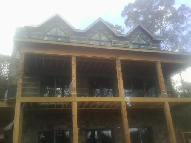 Dormers and porch framing on a large log home under construction — Roof Coating work by our crew in Strafford