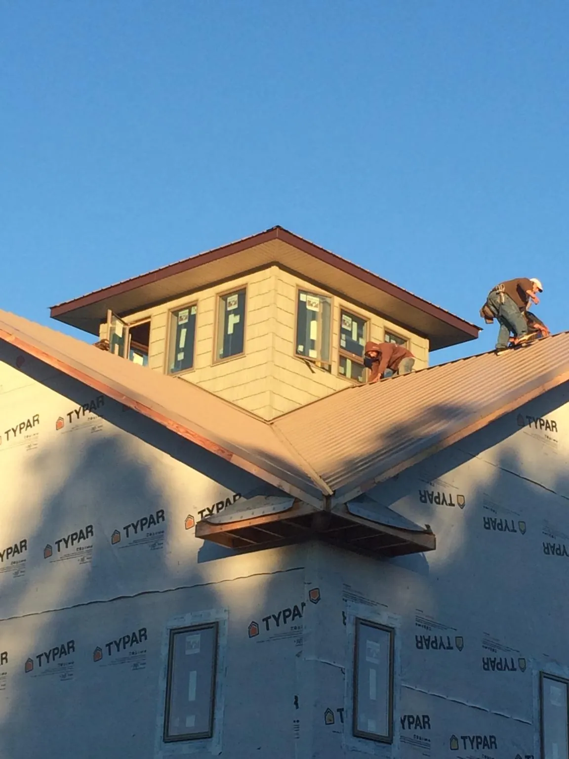 Roofers working around a rooftop cupola on a new metal roof at sunset — Roof Waterproofing in Strafford by Roofing Brothers